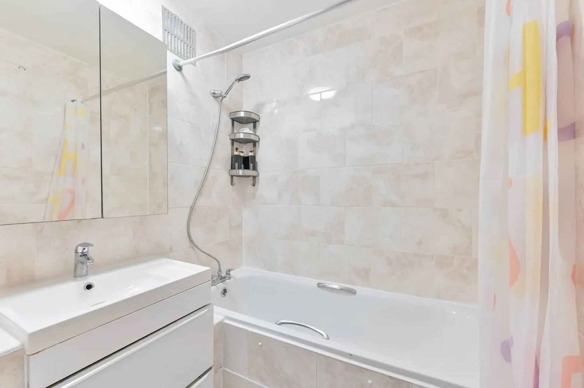 A modern bathroom with a white sink, a bathtub, and a shower.