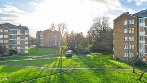 A residential area with multi-story apartment buildings, a grassy courtyard, and a pathway. - Cozy 2-bed Escape in Blackheath Smart Studio (London)