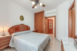 A bedroom with a bed, a nightstand, a lamp, a ceiling fan, and a door leading to another room. - Holiday Home 'Fmr Fielato 15' with Private Terrace (Carboneras)