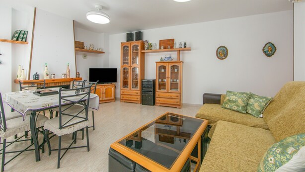 A living room with a sofa, a coffee table, a dining table with chairs, and built-in shelving with decorative items. - Holiday Home 'Fmr Fielato 15' with Private Terrace (Carboneras)