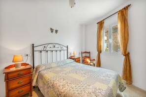 A bedroom with a bed, a nightstand, a chair, a window with curtains, and a wall-mounted light fixture. - Holiday Home 'Fmr Fielato 15' with Private Terrace (Carboneras)