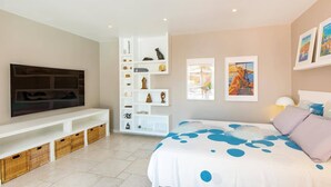 Ein Schlafzimmer mit einem Bett, einem Fernseher, einer eingebauten Schrankwand und Bildern an den Wänden.