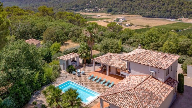 Eine Villa mit Swimmingpool, Sitzgelegenheiten im Freien und Blick auf die umliegende Landschaft.