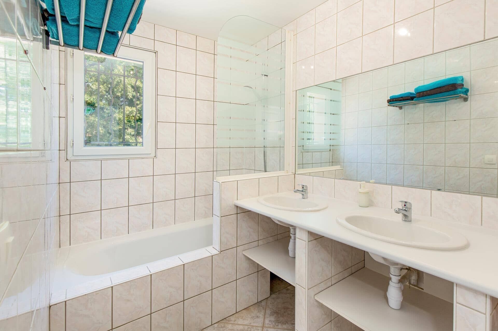 Une salle de bain avec deux lavabos, une baignoire et un grand miroir.