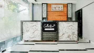 A reception desk with a marble design, a wooden panel above, and a sign indicating it's a company-serviced collection point.
