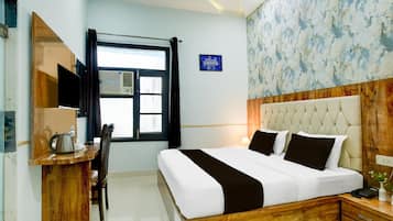 A hotel room with a bed, bedside table, lamp, and a window with curtains.
