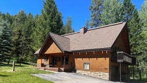 A log cabin with a stone foundation, a chimney, and a porch with outdoor seating.