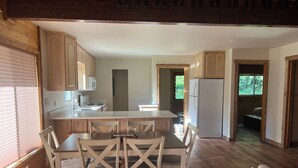 A spacious kitchen with wooden cabinets, a central island, and a dining area with chairs.