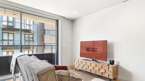 Ein modernes Wohnzimmer mit einem großen Fenster, einem Flachbildfernseher und einem Holzkonsolentisch.