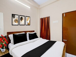 A hotel room with a bed, a nightstand, a potted plant, and three framed artworks on the wall. - Saver Double RKH Inn (Chennai)
