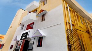 A multi-story building with a white facade, balconies, and a visible sign indicating a business or service. - Saver Double RKH Inn (Chennai)