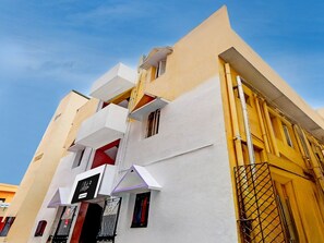 A multi-story building with a white facade, balconies, and a visible sign indicating a business or service. - Saver Double RKH Inn (Chennai)