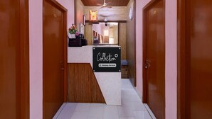A reception area with a marble counter, wooden doors, and a ceiling fan. - Saver Double RKH Inn (Chennai)