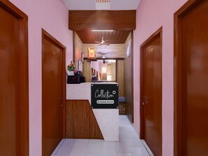 A reception area with a marble counter, wooden doors, and a ceiling fan. - Saver Double RKH Inn (Chennai)
