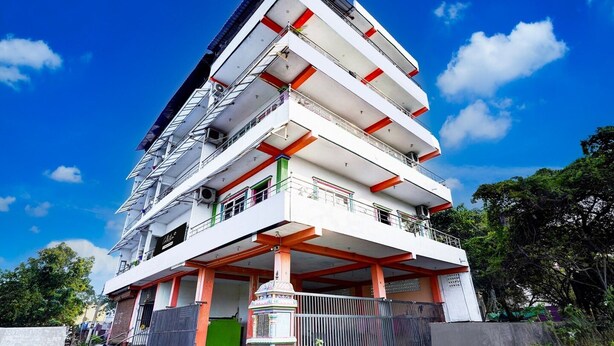A multi-story building with balconies, a gated entrance, and a clear sky. - Super Deluxe Room Ruthran Guest House (Tirukalukundram)