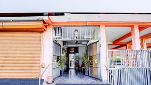 A building entrance with a staircase leading to a covered area, metal railings, and potted plants. - Super Deluxe Room Ruthran Guest House (Tirukalukundram)