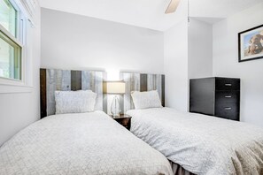 A bedroom with two beds, a nightstand, a lamp, a wardrobe, and a framed picture on the wall. - Coastal Charleston Retreat Near Folly Beach Fun (Charleston)