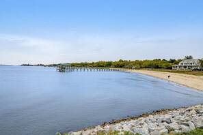 A waterfront property with a pier extending into calm water, a sandy beach, and a large house with a prominent roof. - Coastal Charleston Retreat Near Folly Beach Fun (Charleston)