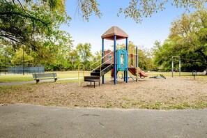 Ein Spielplatz mit Rutsche, Klettergerüsten und einer Bank.
