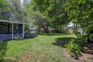 A backyard with a covered patio, a wooden fence, and a variety of trees and shrubs. - Coastal Charleston Retreat Near Folly Beach Fun (Charleston)