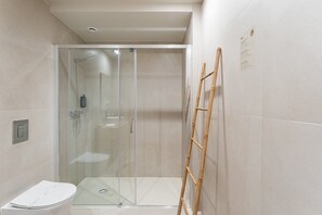 Un baño moderno con cabina de ducha de vidrio, inodoro y escalera de bambú.