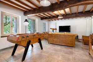 A room with a foosball table, a sofa, a television, and a telescope.