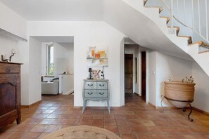 A spacious interior with a staircase, a rustic dresser, and a large window.
