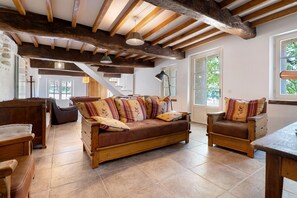 A spacious living area with a wooden sofa, a wooden table, and a staircase leading to an upper level.