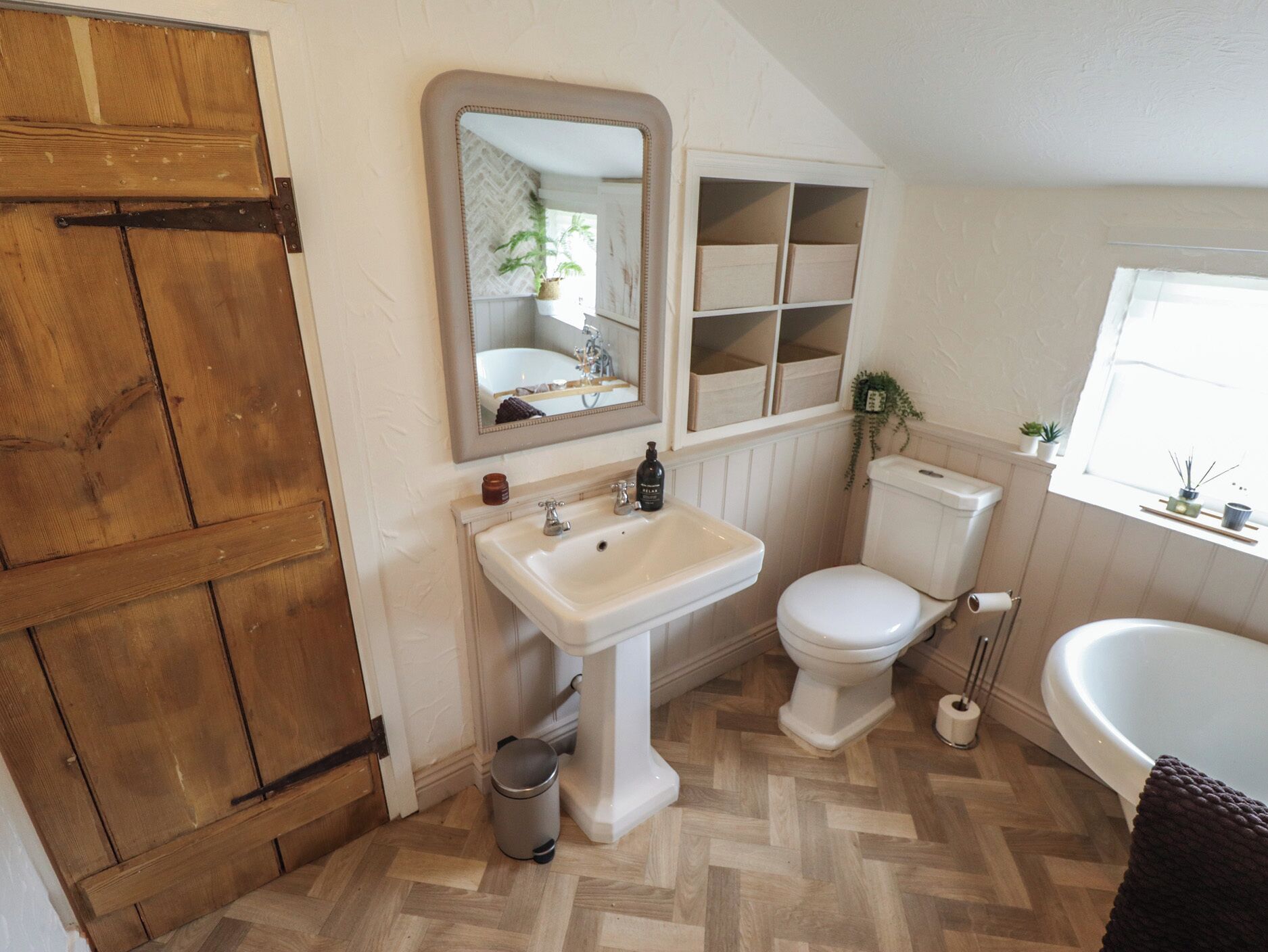 A bathroom with a wooden door, a white sink, a toilet, and a bathtub.