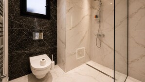 A modern bathroom with a toilet, a shower, and a marble wall. - Chic & Calme – Jardin de Carthage (Tunis)