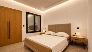 A bedroom with a bed, wooden wardrobe, a mirror, bedside tables with lamps, and a tiled floor. - Chic & Calme – Jardin de Carthage (Tunis)