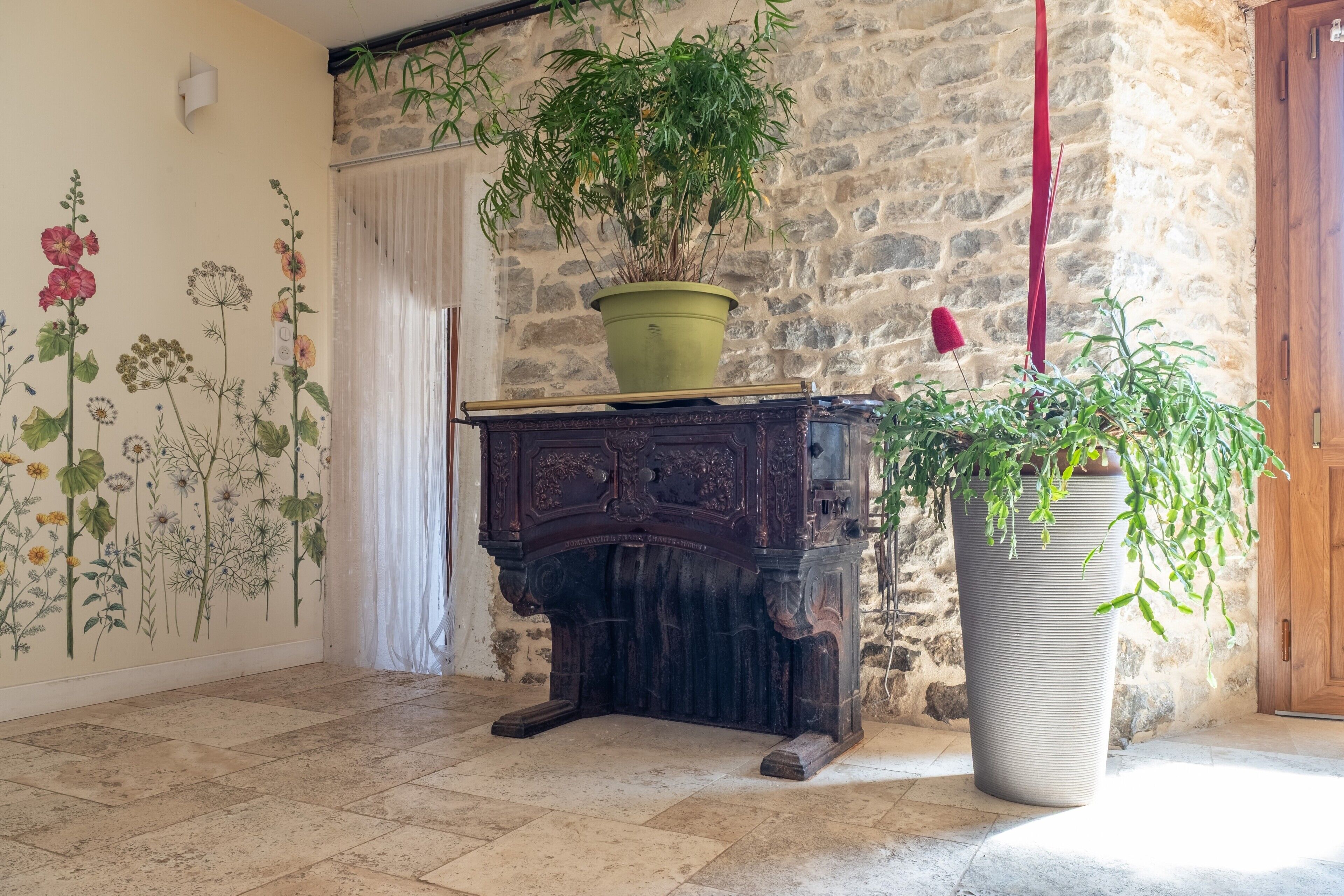 Un mur de pierre, une armoire en bois, une plante verte en pot et une grande plante en pot.