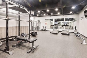 Ein Fitnessstudio mit Gewichte, Laufbändern und einer Bank.
