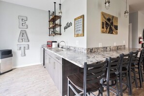 A modern kitchen with a marble island, bar stools, and a large 'EAT' sign on the wall. - 204 Affordable College-Style Apartment, National Parks (Rexburg)