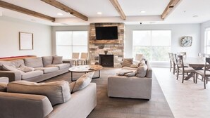 A spacious living room with a stone fireplace, sofas, and a dining area with chairs. - Brigham's Mill Retreat Between Grand Teton & Yellowstone National Parks (Rexburg)