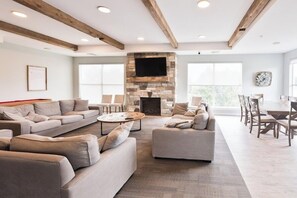 A spacious living room with a stone fireplace, sofas, and a dining area with chairs. - Brigham's Mill Retreat Between Grand Teton & Yellowstone National Parks (Rexburg)