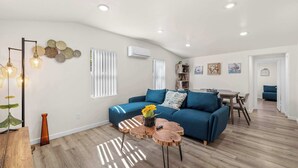 Un salon moderne avec un canapé bleu, une table basse en bois et un coin repas comprenant une table et des chaises.