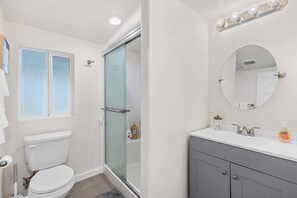 Ein Badezimmer mit Toilette, Duschkabine, Waschtisch mit Spiegel und Waschbecken.