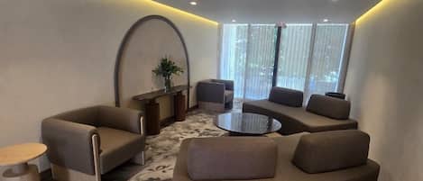 Una sala de estar moderna con un sofá curvo, una mesa de centro redonda y una mesita auxiliar.