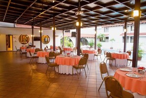 A spacious indoor dining area with round tables covered in white and orange tablecloths, arranged in a U-shape. - Hotel Alameda (Tegucigalpa)