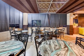 Ein Restaurantinnenraum mit runden Tischen, Stühlen und einer dekorativen Decke.