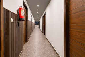 Een gang met houten lambrisering, een brandblusser links en deuren naar kamers.