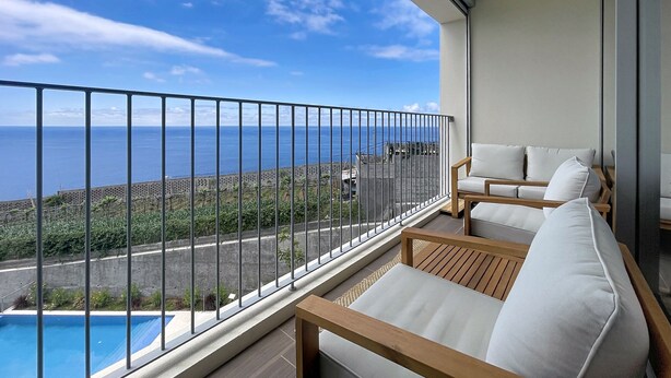 A balcony with a view of the ocean, a pool, and a seating area with cushions. - Azure Atlantic Horizon by Atlantic Holiday (Camara de Lobos)