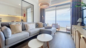 A modern living room with a sofa, two small round tables, a large window with a view of the sea, and a balcony. - Azure Atlantic Horizon by Atlantic Holiday (Camara de Lobos)