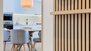 A modern kitchen with a dining area, featuring a wooden panel wall, a pendant light, and a stainless steel oven. - Azure Atlantic Horizon by Atlantic Holiday (Camara de Lobos)