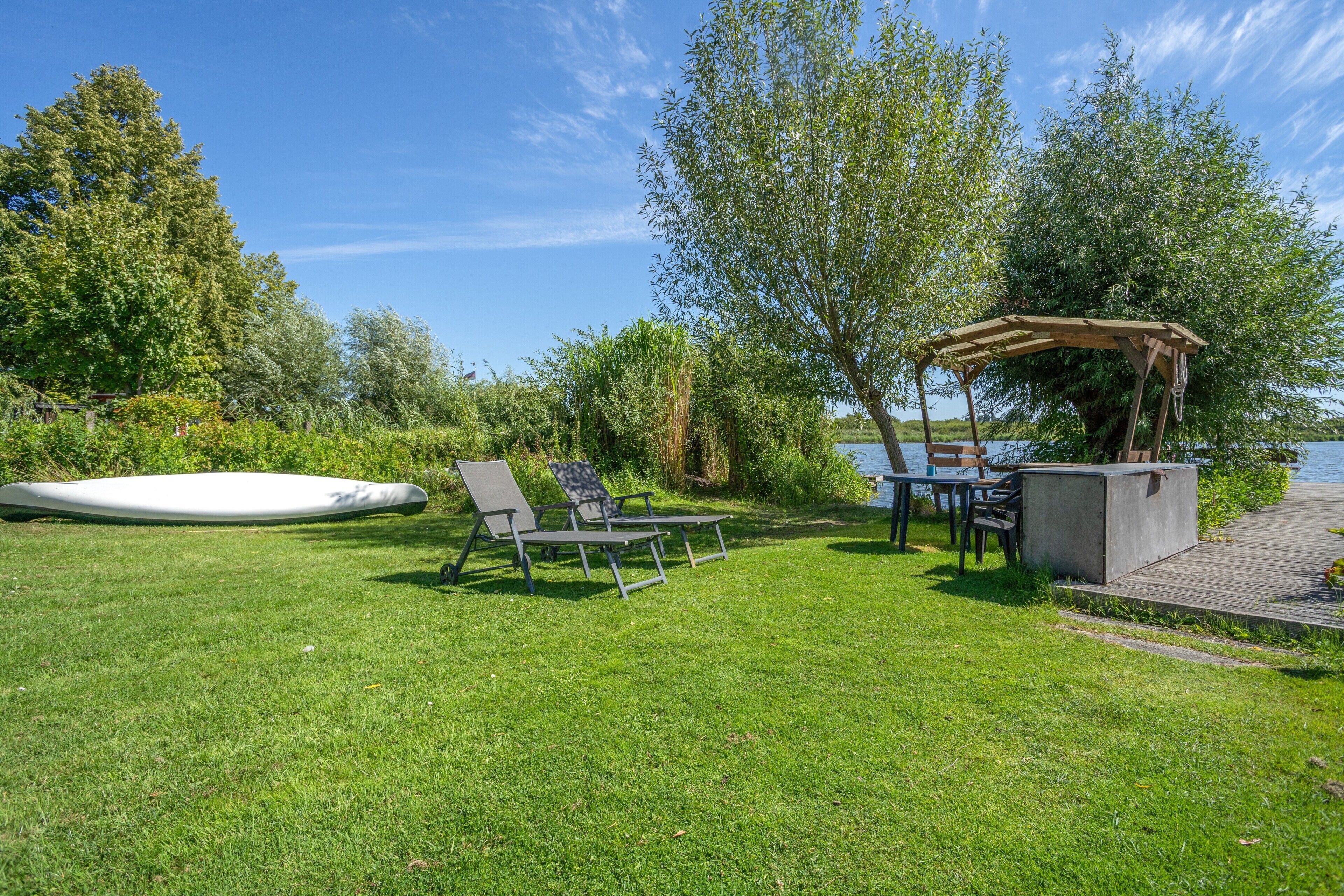 Zona exterior amb gespa, piscina, gandules, taula i una pèrgola.