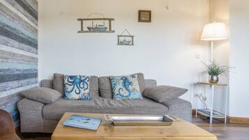 A living room with a grey sofa, decorative pillows, a wooden coffee table, a floor lamp, and a wall with a striped pattern.