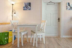 A room with a white door, a table with two chairs, a floor lamp, and two recycling bags. - Apartment 'Fewo Möwe' with Shared Terrace, Shared Garden and Wi-Fi (Röbel)