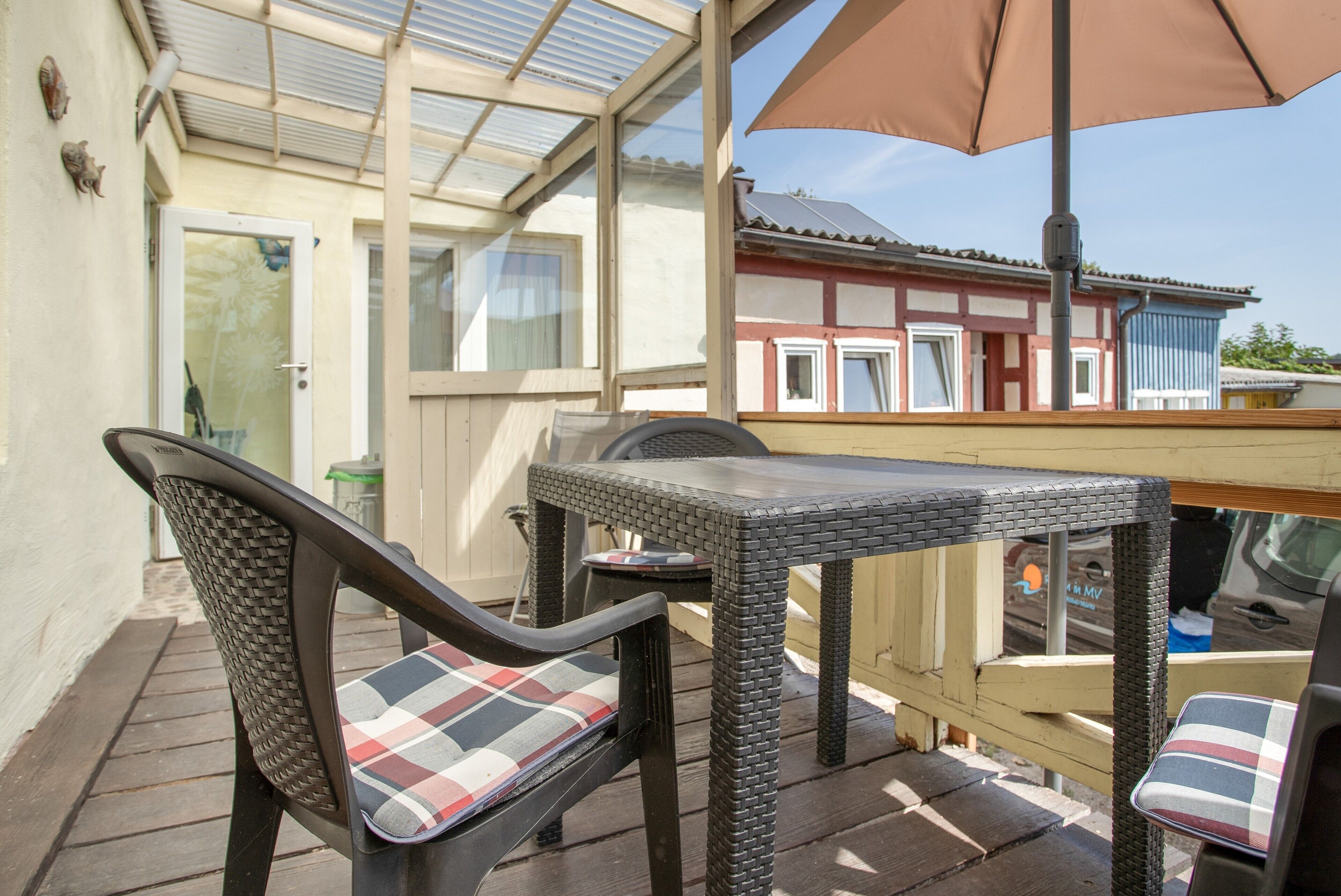 Ein überdachter Patio-Bereich mit Korbmöbeln und einem Tisch.
