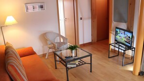 A living room with a sofa, a glass coffee table, a chair, a television, and a door. - Apartment 'Fewo Schwan' with Shared Terrace, Shared Garden and Wi-Fi (Röbel)